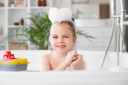 Cute little girl with toy and foam bath taking in bathroom