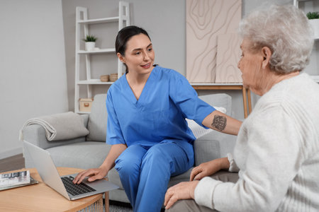Physical therapist using laptop with senior woman at home