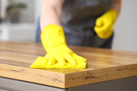 Female janitor cleaning table in kitchen, closeup