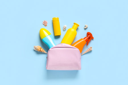 Cosmetic bag with different bottles of sunscreen and seashells on blue backgroundの写真素材