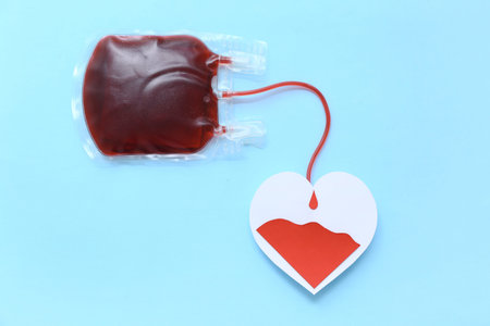 Blood pack with paper heart on blue background. World Blood Donor Dayの写真素材