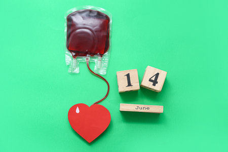 Blood pack, paper heart and calendar with date 14 JUNE on green background. World Blood Donor Dayの写真素材
