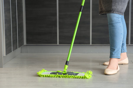 Female janitor mopping floor in kitchen, closeup