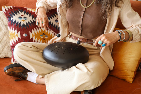 Young witch playing glucophone on sofa at home, closeup