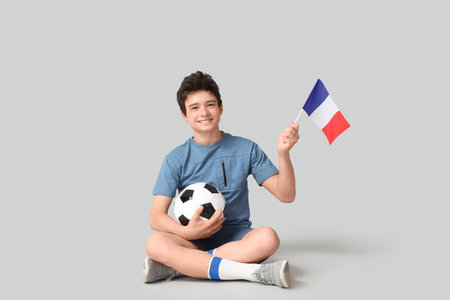 Teenage boy with soccer ball and flag of France on gray backgroundの写真素材