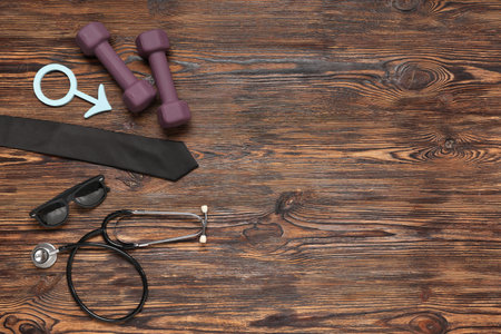 Stethoscope, tie, dumbbells and male sign on brown wooden background. Prostate cancer awarenessの写真素材