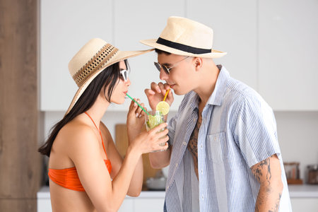 Happy young tourists couple with glass of mojito in kitchenの写真素材