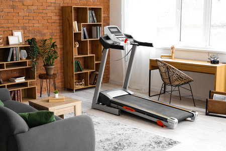 Interior of living room with treadmill, table and shelf units
