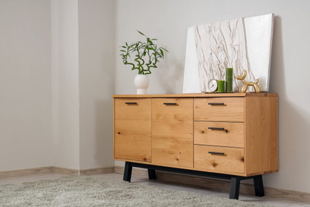 Wooden cabinet with decor, bamboo stems and painting near gray wall