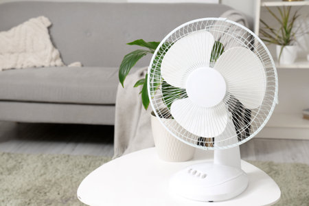 Modern electric fan on coffee table in light living roomの写真素材