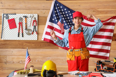 Female Asian worker with USA flag in workshop. Labor Day celebrationの写真素材