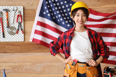 Female Asian worker against USA flag in workshop. Labor Day celebrationの写真素材