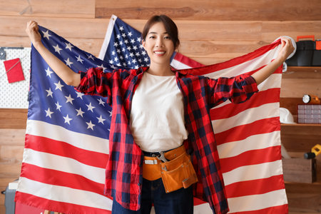 Female Asian worker with USA flag in workshop. Labor Day celebrationの写真素材
