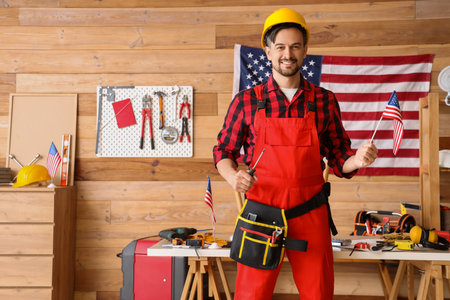 Male worker with USA flag and screwdriver in workshop. Labor Day celebrationの写真素材