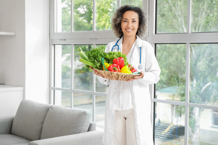 Mature female nutritionist with healthy vegetables in kitchenの写真素材