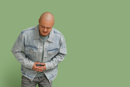 Young man with appendicitis on green backgroundの写真素材