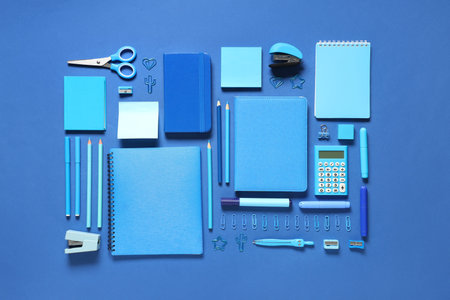 Notebooks and different stationery on blue background