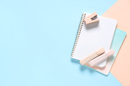 Notebooks, felt-tip pens and stapler on color background