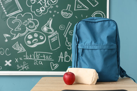 Backpack with pencil case and apple on desk in classroomの写真素材