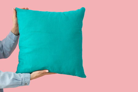 Woman with bright blue pillow on pink backgroundの写真素材