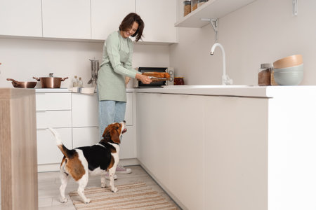 Young woman with bread and Beagle dog in kitchenの写真素材