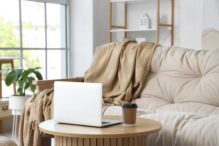 Laptop with cup of coffee on table in living roomの写真素材