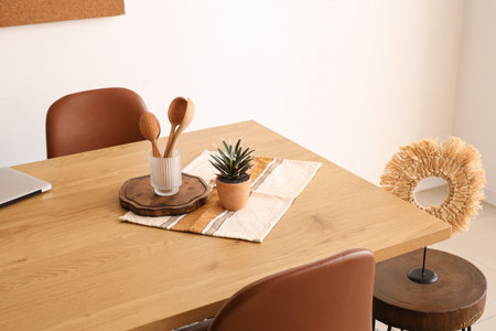 Wooden spoons with plant on dining table in roomの写真素材