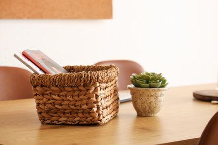 Basket with magazines and plant on dining table in room, closeupの写真素材