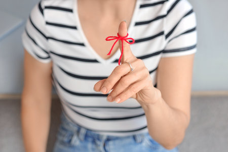 Woman with red string on her finger at home, closeup. Reminder conceptの写真素材