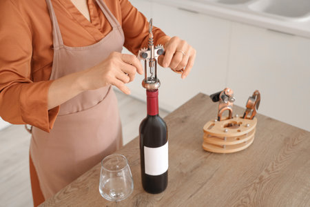 Woman opening bottle of wine at home, closeupの写真素材