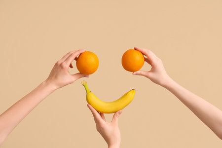 Hands making happy face with fresh oranges and banana on beige backgroundの写真素材