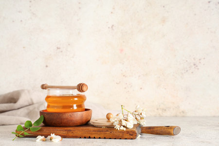 Jar of sweet honey with acacia flowers and dipper on white backgroundの写真素材
