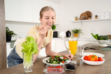 Young woman eating salad with feta cheese in kitchenの写真素材