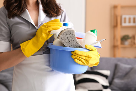 Young chambermaid with cleaning supplies in room, closeupの写真素材