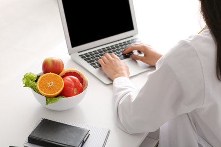 Female nutritionist working with laptop at table in office, closeupの写真素材