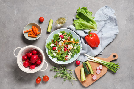 Bowl of fresh salad with feta cheese and different vegetables on gray backgroundの写真素材