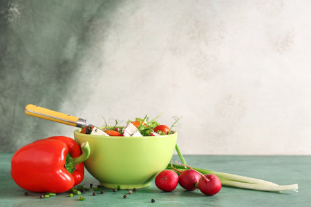 Bowl of fresh vegetable salad with radish and feta cheese on green tableの写真素材
