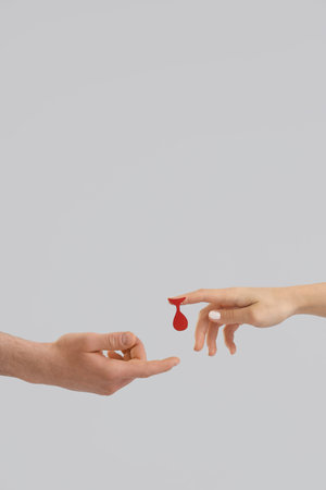 Female blood donor giving paper drop to man on light backgroundの写真素材