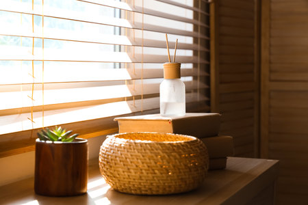 Reed diffuser, books and wicker basket on wooden cabinet at homeの写真素材