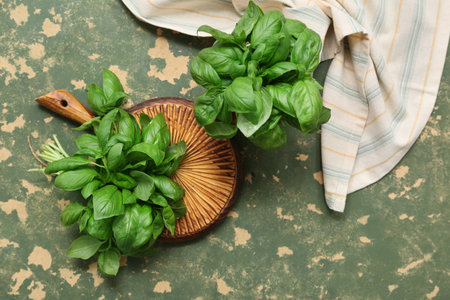 Wooden board with fresh green basil leaves on color backgroundの写真素材