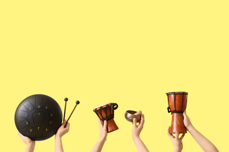 Women with glucophone, Tibetan singing bowl and drums on yellow backgroundの写真素材