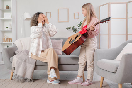 Little girl giving her grandmother guitar at homeの写真素材