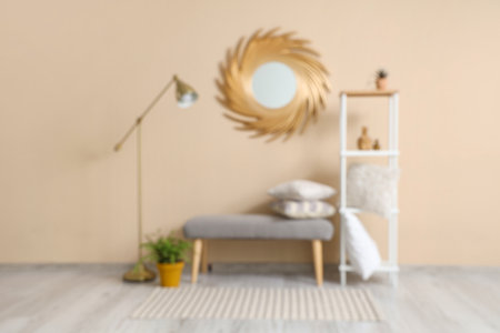 Gray bench, lamp, mirror and shelving unit near beige wall in roomの写真素材