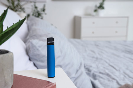 Blue disposable electronic cigarette on bedside table in room