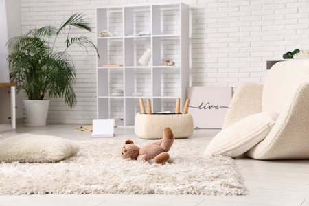 Toy bear on carpet in messy living roomの写真素材