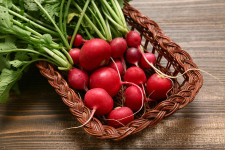 Wicker basket with fresh radishes on wooden background