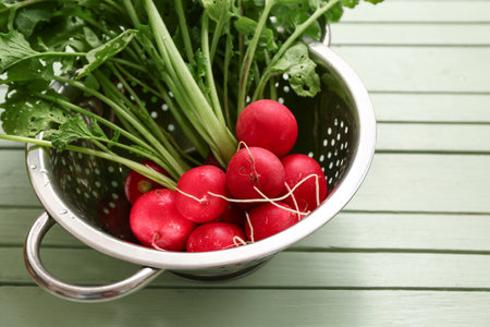 Colander with fresh radishes on green wooden backgroundの写真素材