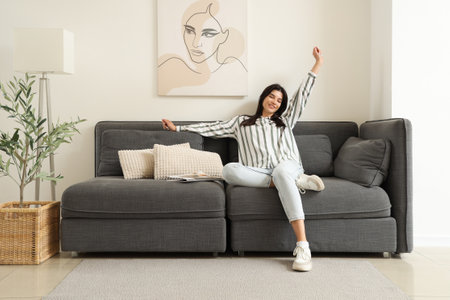 Young woman resting on black sofa in living roomの写真素材