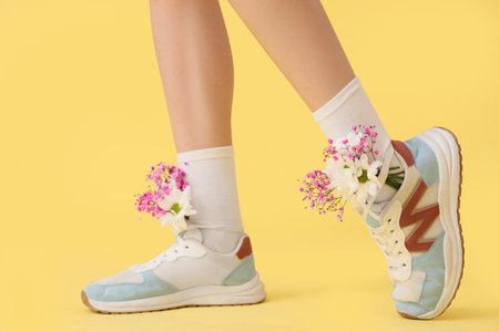 Female legs in sneakers with different flowers on yellow backgroundの写真素材