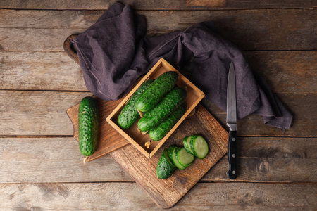 Box and boards with fresh green cucumbers on wooden backgroundの写真素材